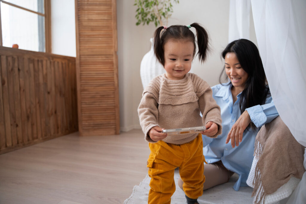 a child walks as her mother watches over her
