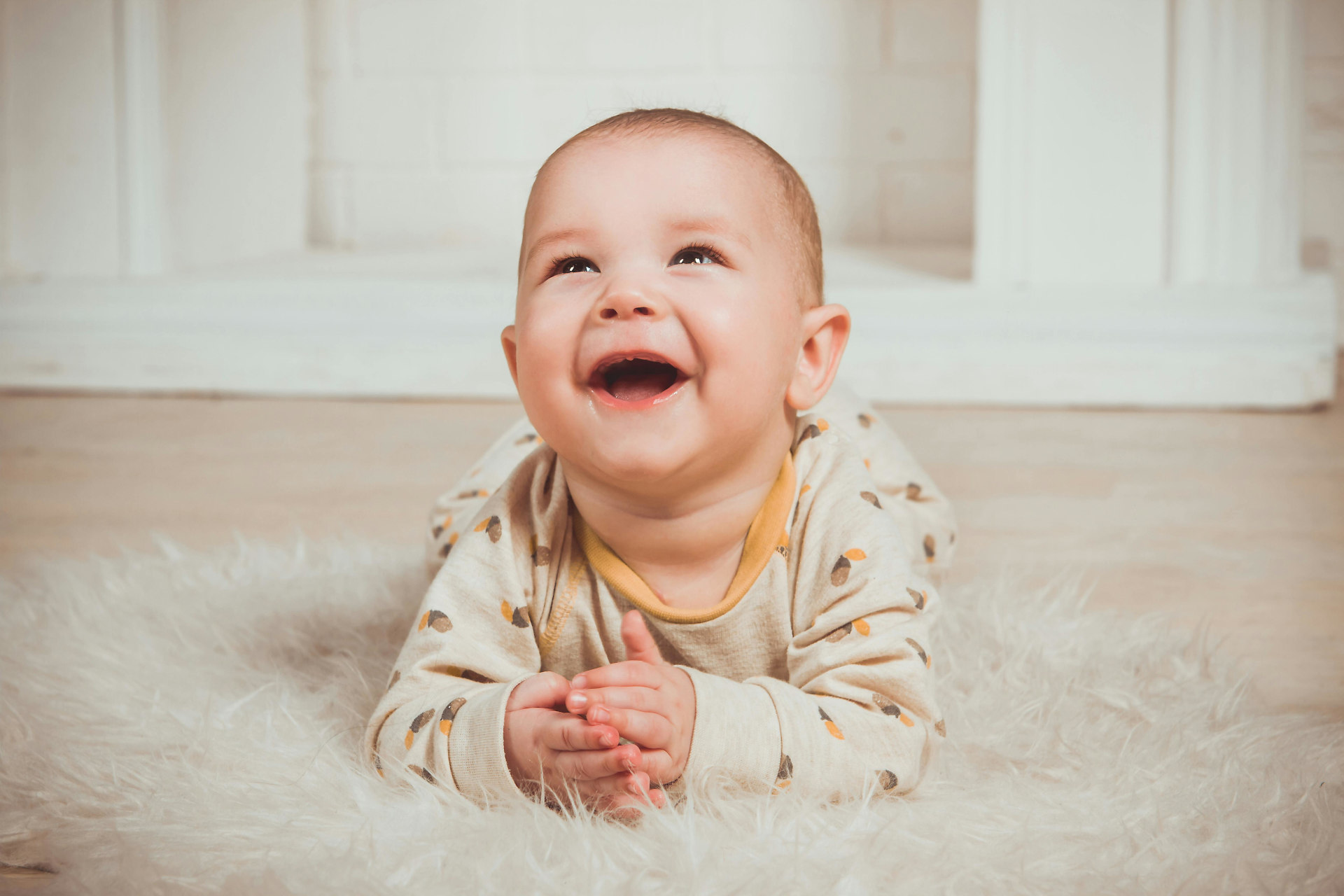 An infant propped up on their arms and smiling.